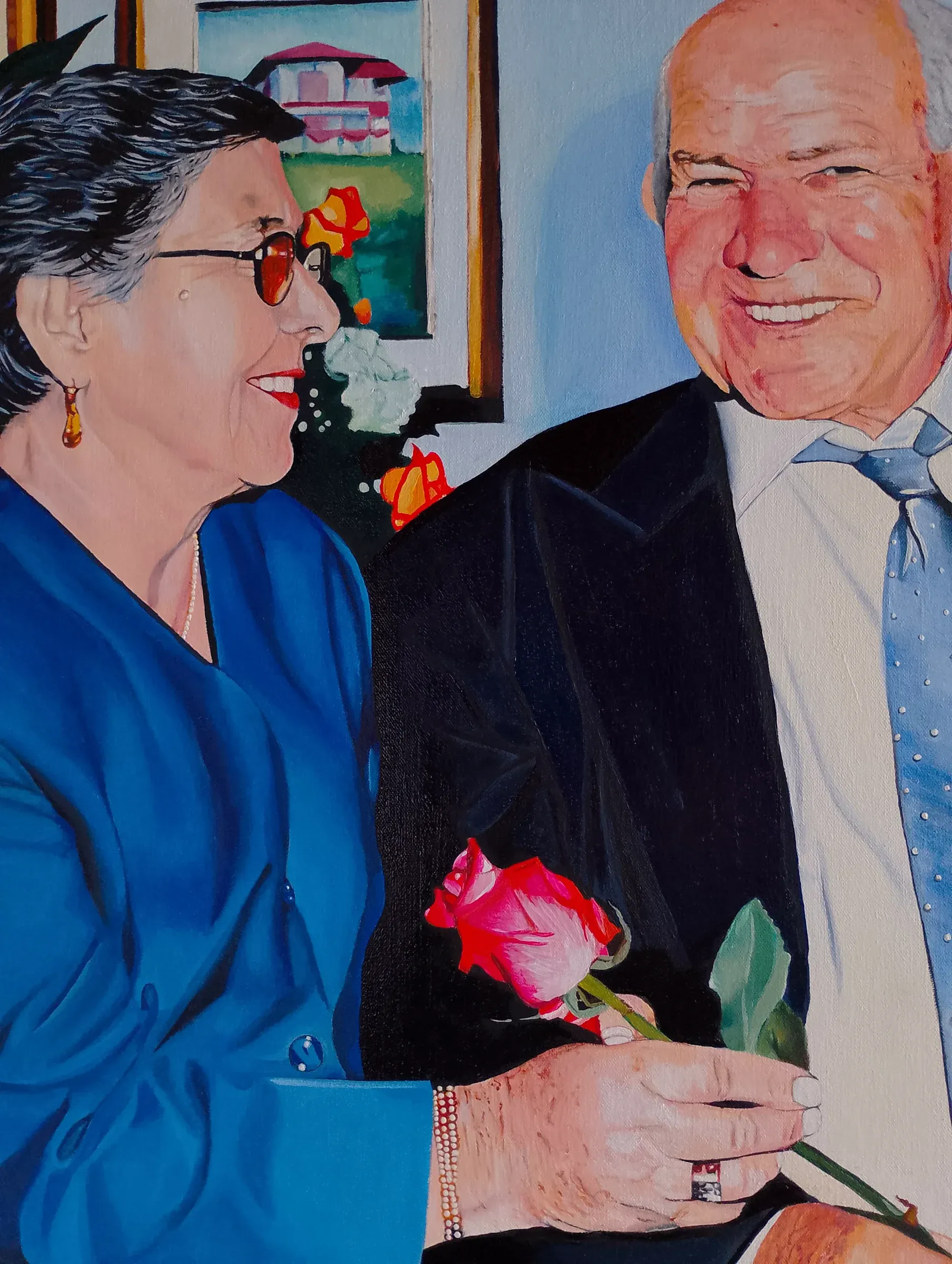 Retrato de una pareja mayor sonriente; él sostiene una rosa roja