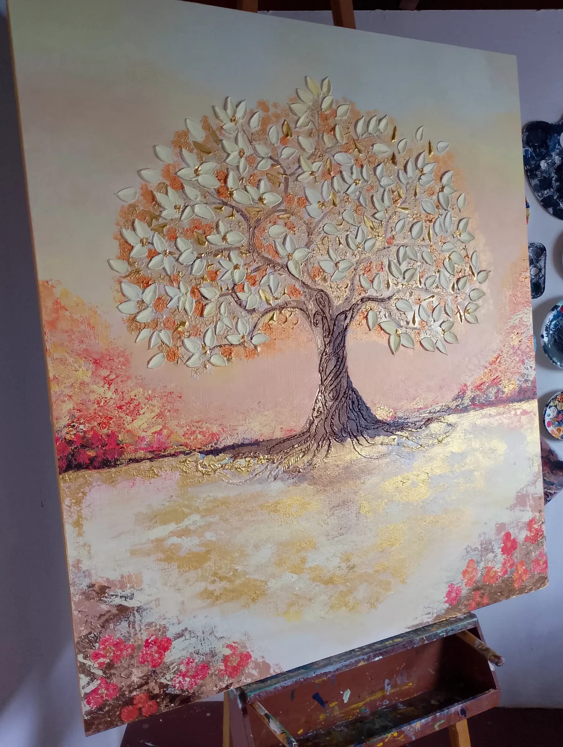 Árbol de hojas doradas en relieve sobre un paisaje de tonos rosados y crema